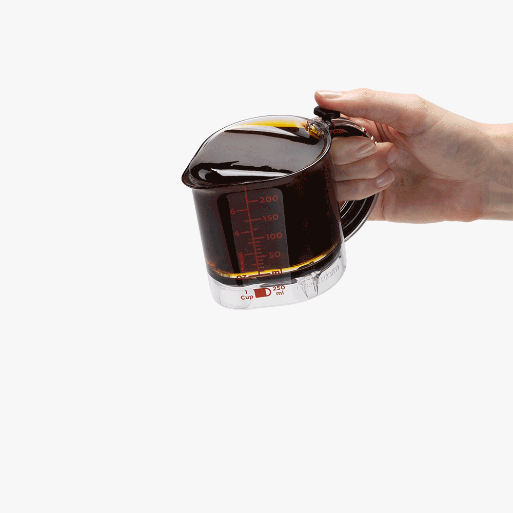 Dreamfarm Upcup 計量カップの底を押し上げて粘り気のある調味料を残さず押し出す様子